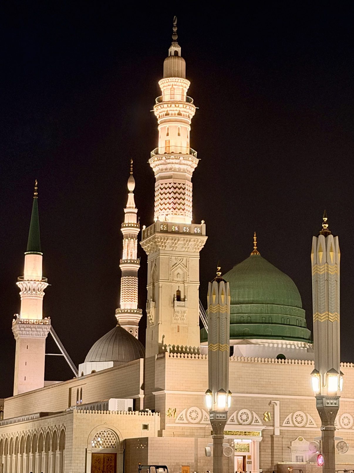 The Prophet's Mosque at night, minarets lit against the dark sky