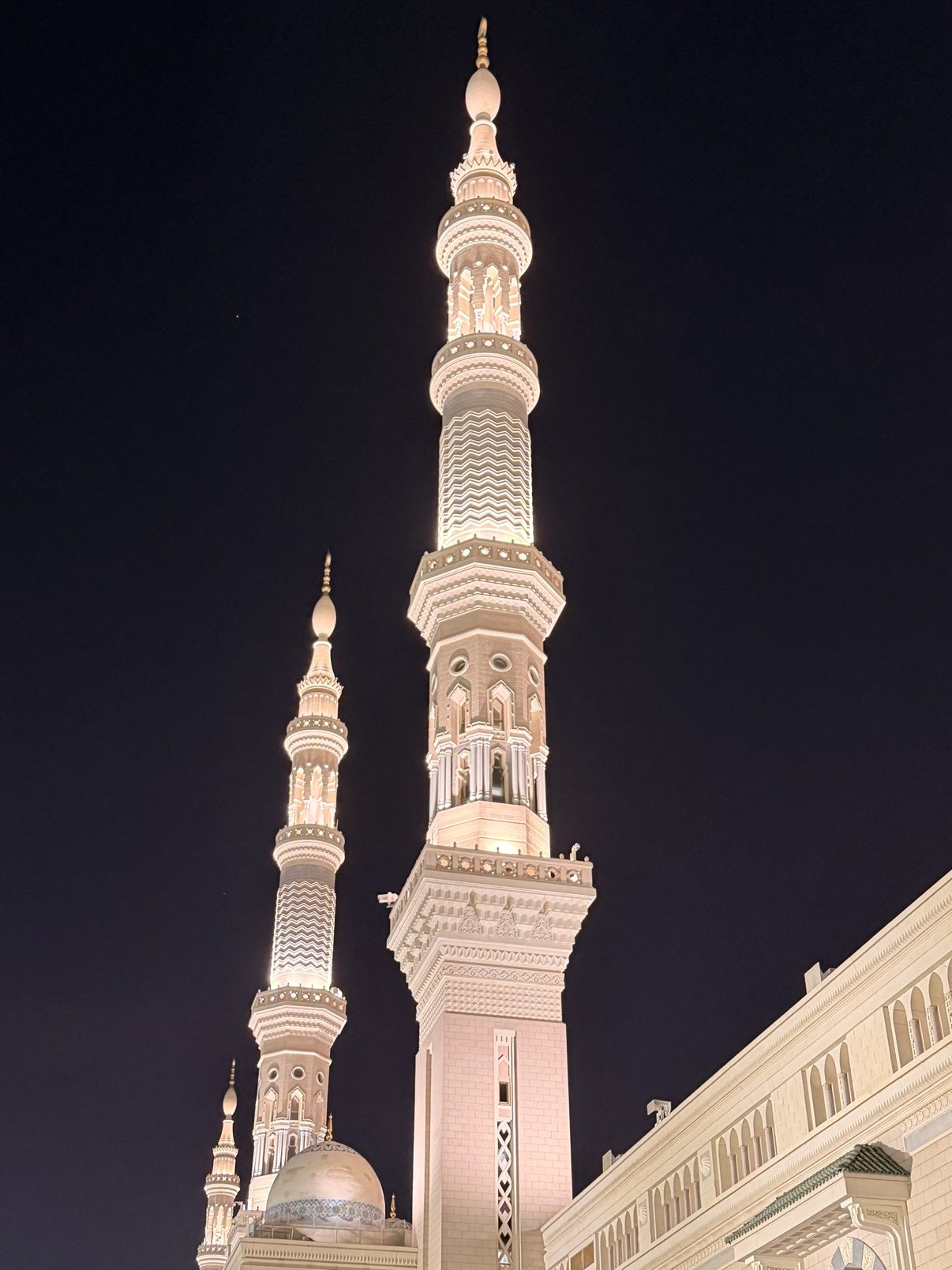 A minaret of the Prophet's Mosque illuminated at night