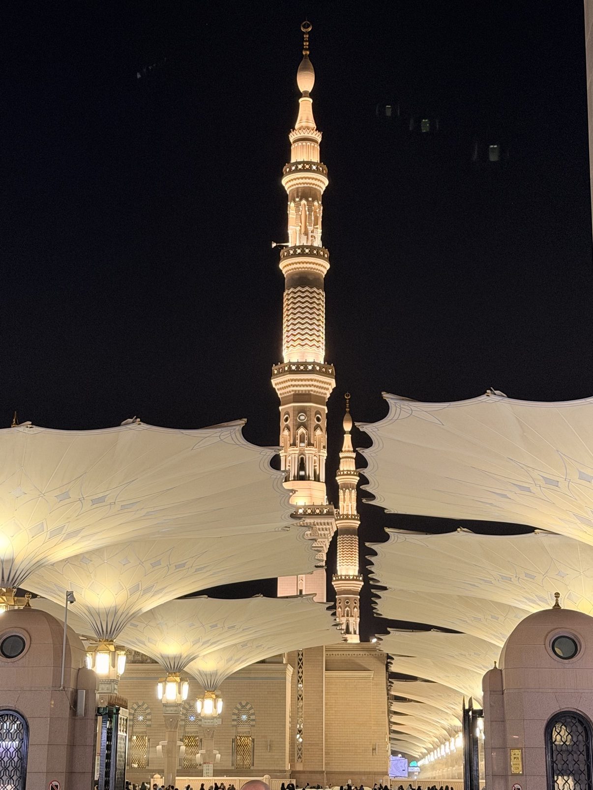 The courtyard umbrellas of the Prophet's Mosque under a night sky