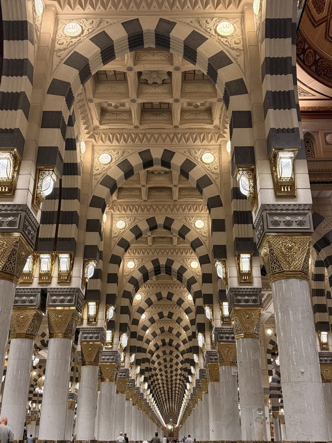 Rows of black-and-white striped arches receding inside the Prophet's Mosque