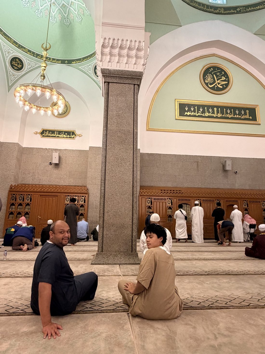 Two members of the group resting on the carpet inside Masjid Quba