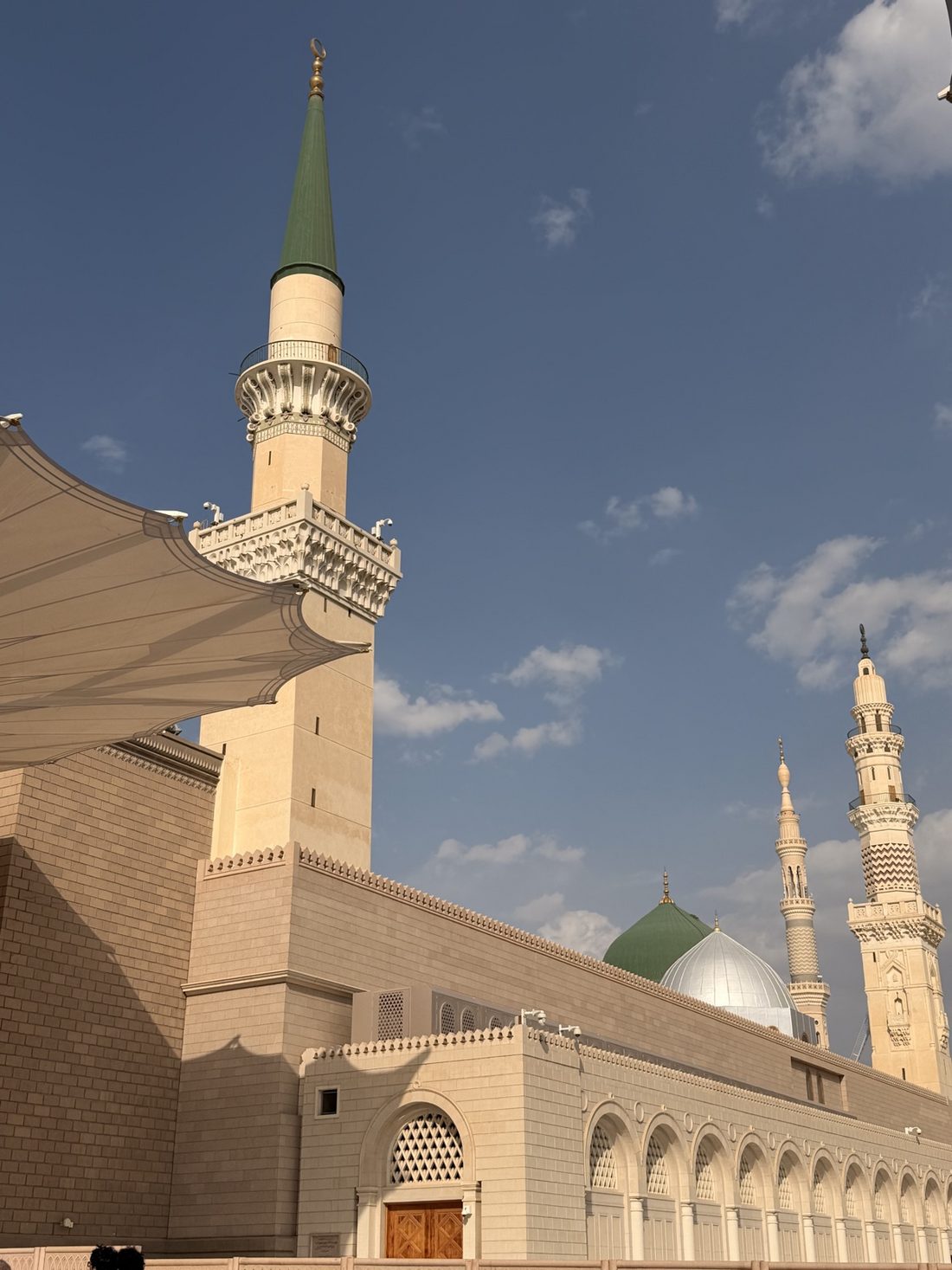 The Green Dome and minarets of the Prophet's Mosque under a blue daytime sky