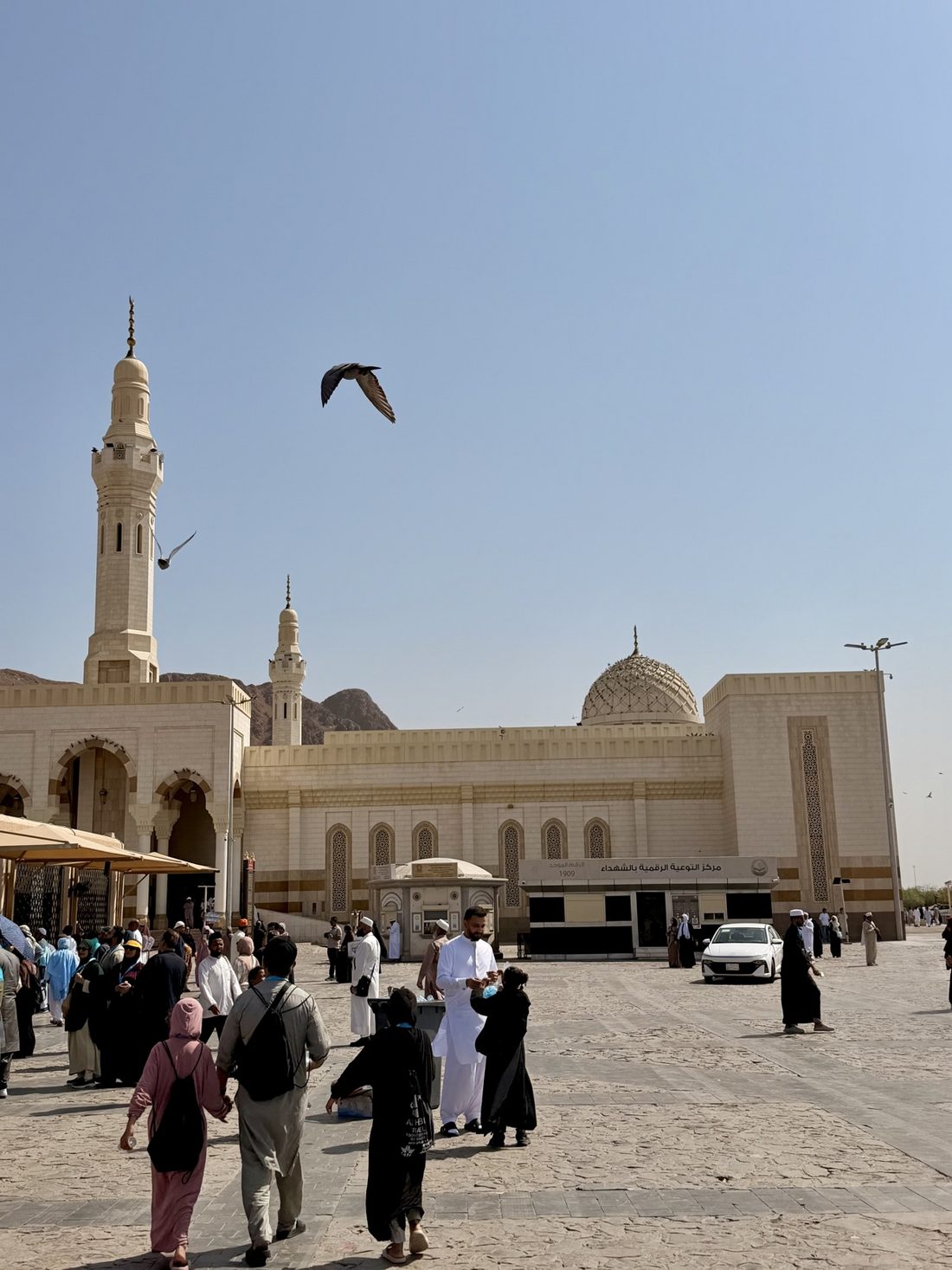 The Sayyid al-Shuhada mosque at Uhud, visitors crossing its plaza with the mountain behind