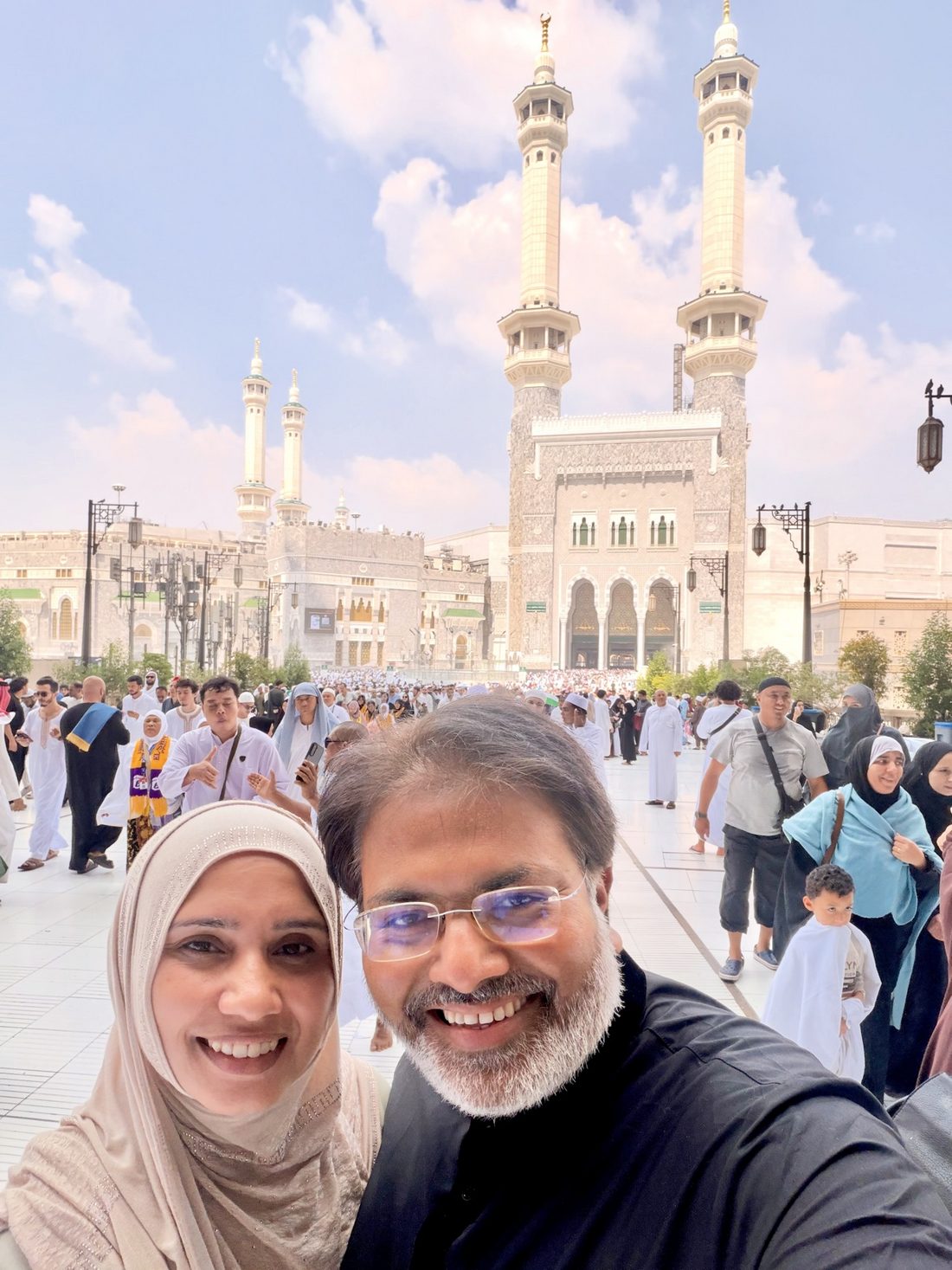 The group's guides smiling in the courtyard of Masjid al-Haram in Makkah, pilgrims all around